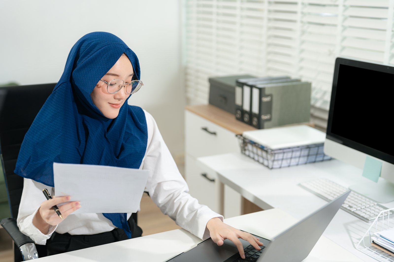 Staf menyemak dokumen gaji di komputer